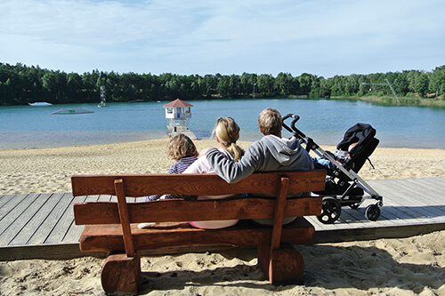 Familie sitzt auf einer Bank am Strand