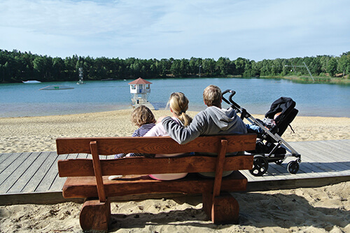 Familienzeit erleben im Bernsteinsee Hotel & Ferien Familie sitzt auf einer Bank am Strand