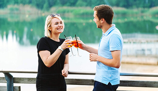 Paar feiert mit Cocktails auf der Seeterrasse