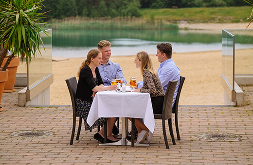 Zwei Paare beim Abendessen auf der Strandterrasse